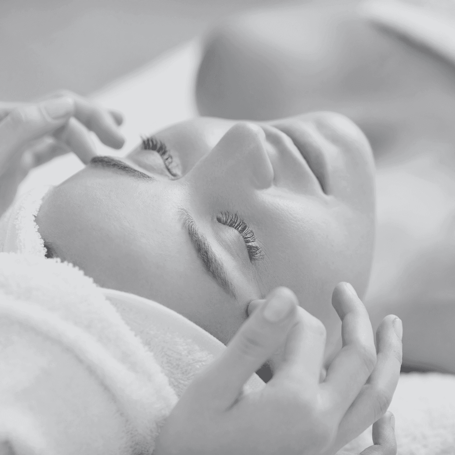 Person enjoys a facial massage, eyes closed, with hands gently pressing on their face.